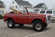 an old red truck with a surfboard strapped to the back