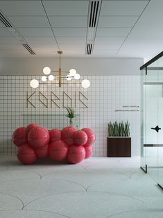 a room with white tiles and red balloons on the floor in front of a plant