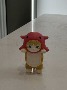 a small toy cat with a red hat on it's head standing on a counter