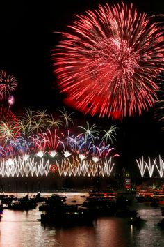 fireworks are lit up in the night sky over water