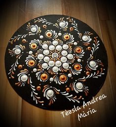 a black plate with orange and white designs on it sitting on a wooden table top