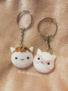 two white cats with pink bows on their heads are sitting next to each other in key chains