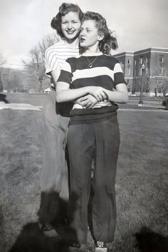 an old black and white photo of two young women hugging each other in the grass