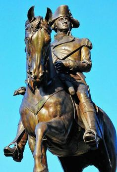 a statue of a man riding on the back of a horse in front of a blue sky