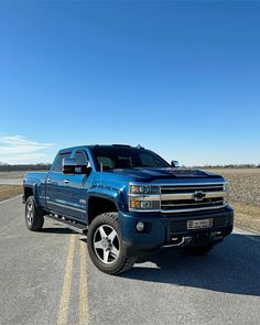 a blue truck is parked on the side of the road in front of an empty field