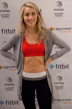 a woman standing in front of a wall with her hands on her hips and smiling