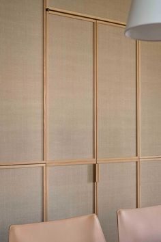 two white chairs sitting in front of a wall with wooden paneling on the walls