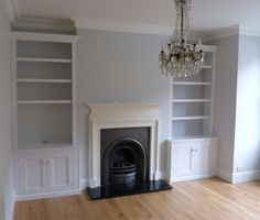 empty living room with fireplace and built - in bookcases, chandelier