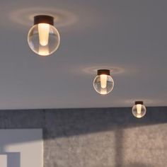 three lights are hanging from the ceiling in a room with gray walls and carpeted flooring