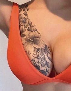 the back of a woman's breast with flowers on it and an orange tank top