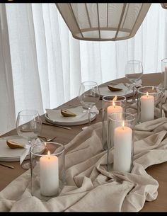 a table set with white candles and place settings