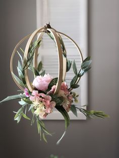 a flower arrangement hanging from a chandelier with greenery and flowers in it