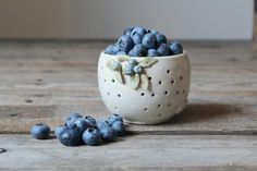 a white bowl filled with blueberries on top of a wooden table