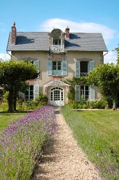 the house is surrounded by lavender flowers and trees