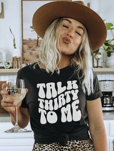 a woman wearing a black shirt and leopard print skirt holding a wine glass in her right hand