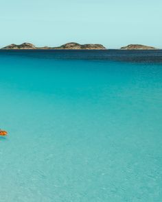 two people are in the water on their surfboards with an island in the background