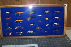 a display case filled with lots of different types of fishing lures on blue felt