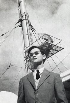 a man in a suit and tie standing next to a radio tower