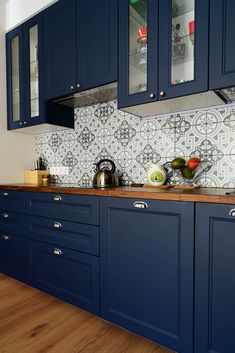 a kitchen with blue cabinets and wooden counter tops in front of a tiled backsplash