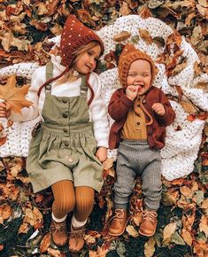 two dolls laying on top of leaves in the grass with one holding his mouth open