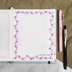 an open notebook with a pink pen on top of it next to a black ballpoint pen