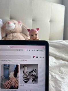 a laptop computer sitting on top of a bed next to a stuffed animal and doll