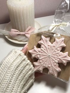 a hand holding a cookie in front of a candle and some other items on a table