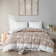 a bed with white and brown comforters in a bedroom next to a wall hanging