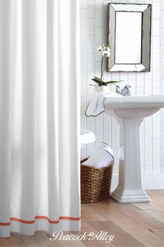 a white shower curtain in a bathroom next to a sink and mirror with flowers on it