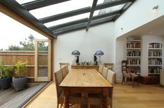 a dining room table with chairs and bookshelves in front of an open window