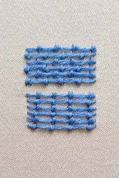 two pieces of blue thread sitting on top of a white surface