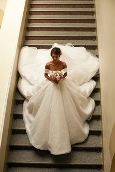 a woman in a wedding dress is walking down the stairs