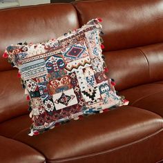 a brown leather couch with a decorative pillow on top of it's backrest