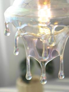 a glass table with water droplets hanging from it's top and the light shining through