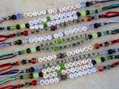 four bracelets with words written on them and beaded in white, green, red, and black beads