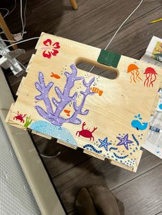 a child's wooden board with sea animals and marine life painted on it sitting on the floor