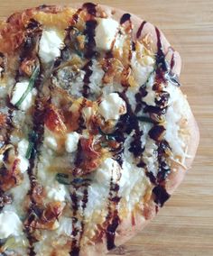 a pizza with cheese and other toppings on it sitting on a wooden table top