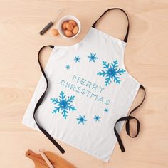 a white apron with blue snowflakes on it next to some wooden utensils