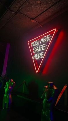 people standing in front of a neon sign that says you are safe here