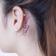 a close up of a person's ear with a flower tattoo on the back of their left ear