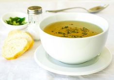 a bowl of soup on a plate next to bread