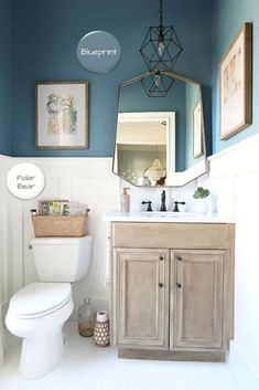 a white toilet sitting under a bathroom mirror next to a sink with a basket on top of it