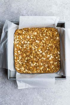 an overhead view of a loaf of granola bread in a baking pan with parchment paper on the side