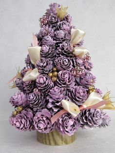 a small purple christmas tree made out of pine cones and other decorative items on a white background