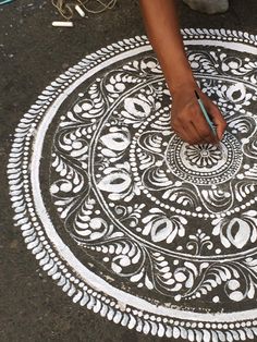 a person is drawing on the ground with white chalk and markers in front of them