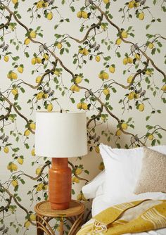 a lamp on a table in front of a wallpaper with lemons and leaves