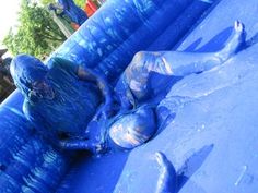 a person laying on top of a blue inflatable structure with trees in the background