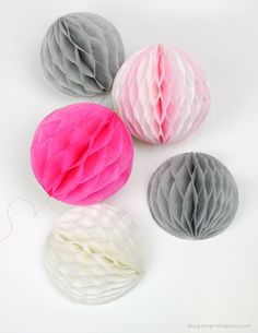 four different colored paper balls on a white surface with one pink and one grey ball in the middle