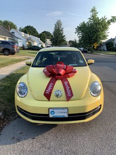 a yellow car with a red bow on the hood