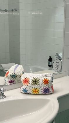 a white sink sitting under a bathroom mirror next to a bathtub with two towels on top of it